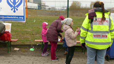 -Ukrainian-refugee-children-and-mothers-eating-sweets-on-Polish-border,-survivors-of-Russian-attacks-have-a-respite-after-escaping-war-invasion
