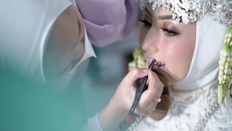 Beautiful-young-muslim-bride-and-groom-applying-wedding-makeup-by-makeup-artist