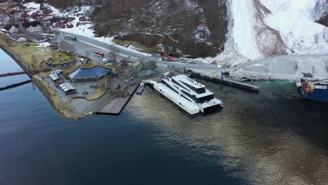 Passenger-boat-with-unique-design-named-Vision-of-the-fjords-alongside-in-Gudvangen-Norway---Aerial-rotating-around-vessel-with-hotel-and-river-on-the-side