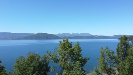 Arboles-Rodean-Lago-Azul-En-El-Sur-De-Chile,-Montañas-Verdes-Adornan-El-Paisaje
