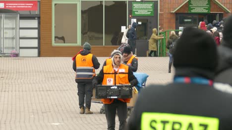 A-volunteer-relief-worker-carries-a-basket-while-Ukrainian-refugees-stand-in-line-for-assistance