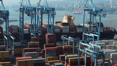 Ausleger-Von-Containern,-Die-In-Der-Nähe-Von-Kränen-Gestapelt-Sind-Und-Bereit-Sind,-Auf-Ein-Frachtschiff-Geladen-Zu-Werden,-Das-Im-Seehafen-Von-Valparaiso,-Chile,-Angedockt-Ist