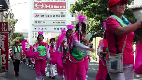 Bailarines-Asiáticos-Ondeando-Grandes-Cintas-Rosas-Durante-El-Desfile-Callejero