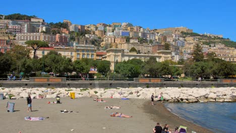 Shot-of-people-relaxing-and-sunbathing-on-Mappatella-Beach-on-Quay-of-Via-Francesco-Caracciolo-in-Naples,-Italy-on-a-sunny-summer-day