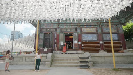Jóvenes-Turistas-Caucásicas-Toman-Fotos-Y-Ven-La-Ceremonia-Budista-Dentro-Del-Templo-Bongeunsa-En-Seúl,-Corea-Del-Sur