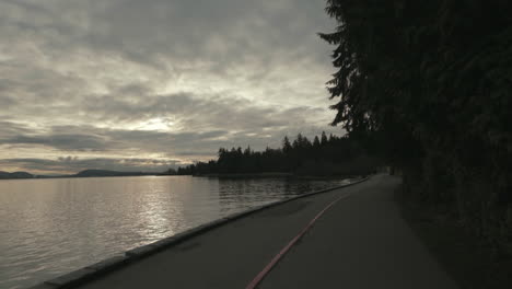 Breite-Rückwärts-Bewegende-Aufnahme-Eines-Stanley-Park-Seawall-Trail-In-Dunkler-Morgenatmosphäre,-Vancouver,-Slowmotion