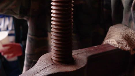 Close-up-of-screw-threads-on-antique-cider-press-being-turned