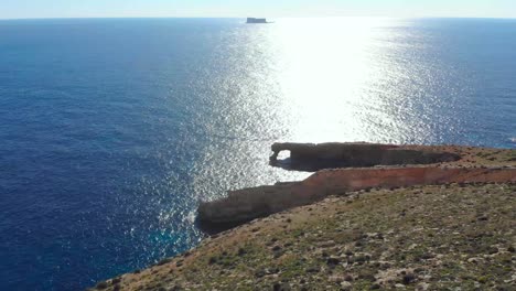 Drone-Disparó-Sobre-Rocas-En-La-Naturaleza-Y-Hacia-Una-Ventana-De-Piedra-Y-Una-Filfla---Una-Pequeña-Isla-En-El-Mar-Mediterráneo-De-Malta