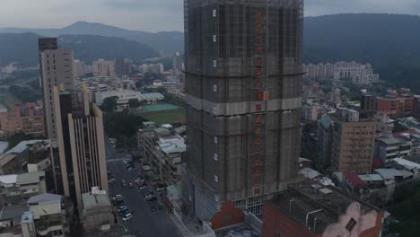 Drone-shot-of-an-unfinished-building,-focused-on-the-elevator-going-down-then-the-street-is-revealed