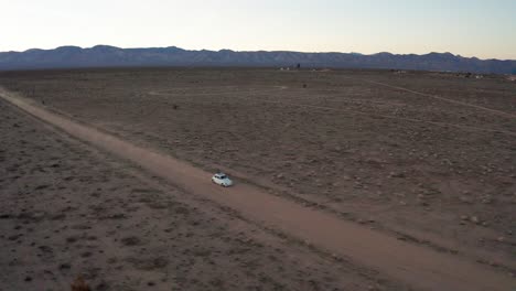 Aerial-Flying-Backward-Tracking-White-Car-Driving-in-Mojave-Desert