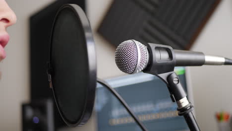 Close-up-on-a-studio-vocal-microphone-with-a-vocalist-singing-into-it-during-a-podcast-recording-session-in-a-bedroom-music-studio