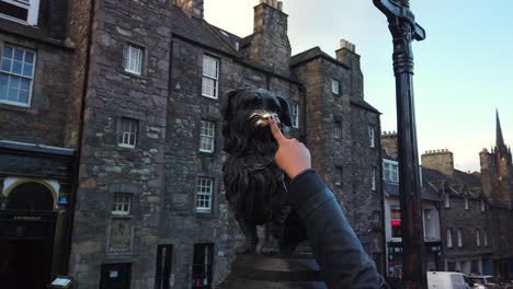 A-woman's-finger-enters-frame-to-touch-the-nose-of-the-famous-Greyfriar's-Bobby-statue-on-Candlemaker-Row,-Edinburgh,-Lothian,-UK