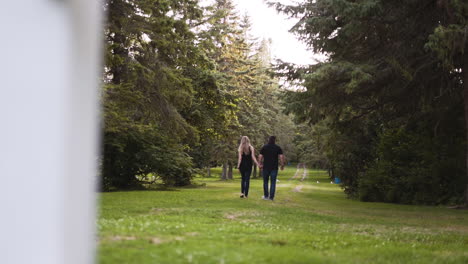 Young-couple-walking-on-a-dirt-trail-in-a-beautiful-forest