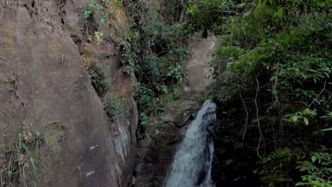 Slow-panning-down-movement-showing-a-waterfall-emerging-from-the-thick-tropical-mountain-forest-of-Rio-de-Janeiro-down-to-the-mouthing-of-it-into-a-pond