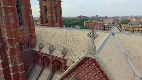 Aerial-view-of-a-Church-top-with-city-in-the-background-,-A-black-kite-sit-on-the-Church