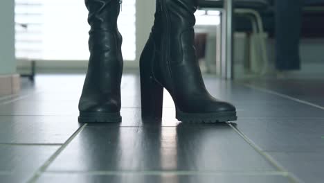 Girl-struts-in-front-of-the-close-up-camera-in-black-faux-leather-high-heels-block-heel-boots-around