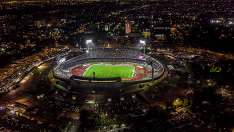 Aerial-hyperlapse-of-the-Ciudad-Universitaria-Olympic-Stadium-in-a-futbol-soccer-game-at-night