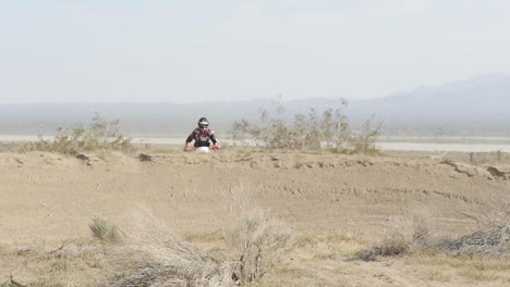 SLOW-MOTION:-A-dirt-biker-jumps-off-a-berm-in-the-desert-on-his-motorcycle