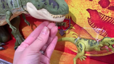 Close-up-of-a-hand-opening-and-closing-the-jaws-of-a-boxed-T-Rex-action-figure-from-the-Jurassic-World-Legacy-Collection-made-by-Mattel
