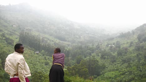 Two-young-African-girls-stare-out-into-a-lush-green-valley-in-rural-Uganda