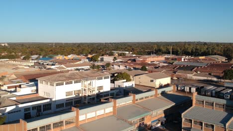 Eine-Herunterziehbare-Drohnenaufnahme-Von-Industriegebäuden-Am-Rande-Von-Bulawayo,-Simbabwe-Bei-Sonnenuntergang