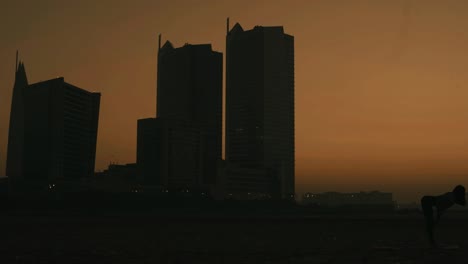 Silhouette-Einer-Frau,-Die-Yoga-Am-Clifton-Beach-Gegen-Orangefarbenen-Sonnenunterganghimmel-In-Karachi-Macht