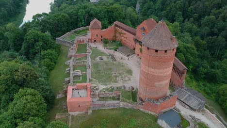 Aerial-standing-shot-of-Turaida´s-Castle,-with-people-walking-in-the-main-courtyard