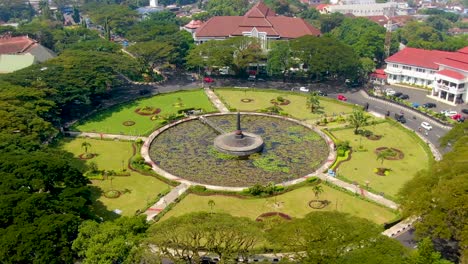 Aerial-city-hall-and-park-with-pond-and-statue-at-Tugu-Square,-Malang,-Indonesia