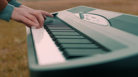 Playing-the-piano,-keyboard-outside-with-a-coat-on-in-close-up