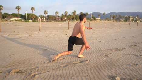 muscular-athlete-training-legs-on-the-beach-doing-lunges-crouching