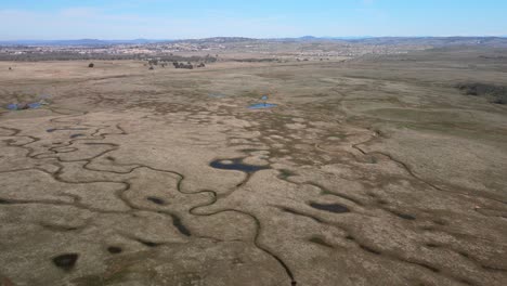 Realtime-drone-footage-over-Prairie-City-country-park,-California,-USA,-showing-wide-open-scrubland-countryside-and-waterways,-on-a-warm-morning-with-blue-sky