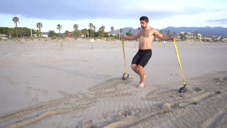metabolic-workout-on-the-beach-with-muscular-man-performing-back-and-rubber-variant-with-kettlebell