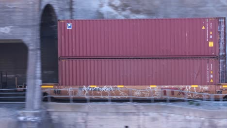 Panning-clip-of-container-cars-passing-through-short-cliffside-tunnels