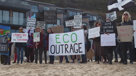 Young-boy-joins-demonstrators-standing-together-on-beach-against-Carbis-Bay-Hotel,-Cornwall