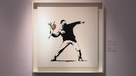 Banksy-art-piece-named-"Love-is-in-the-air"-,-depicting-a-protestor-caught-in-the-act-of-hurling-a-bouquet-of-colorful-flowers-instead-of-a-Molotov-cocktail,-at-Sotheby's-show-in-Hong-Kong