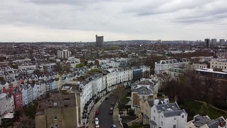 Ascending-aerial-wide-shot-over-Notting-Hill-District-with-colorful-buildings-in-housing-area-during-cloudy-day