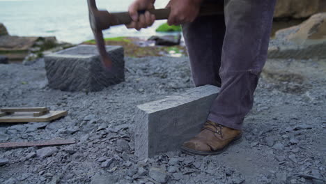 Handheld-shot-of-a-master-craftsman-shaping-a-cancagua-stone-with-a-hand-tool-in-the-city-of-Ancud-of-the-shoreline-of-Chiloe-Island