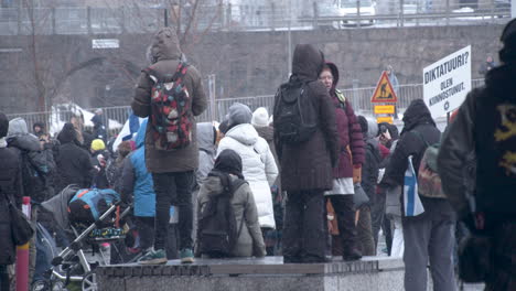 Medium-wide-shot-of-a-crowd-of-people-protesting-against-covid-19-restrictions,-grey-cold-day