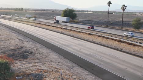 Car-and-trucks-drive-interstate-10-highway-amid-arid-California-landscape