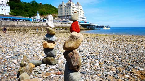 Colourful-rocks-arrangement-balanced-on-sunny-Llandudno-beach-seaside-shoreline-dolly-right