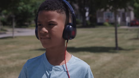 Young-African-american-kid-close-up-listening-to-music-outdoors-on-headphones