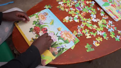 Afrikanisches-Armes-Kind,-Das-Im-Waisenhaus-Ein-Cartoon-Kinderpuzzle-Spielt