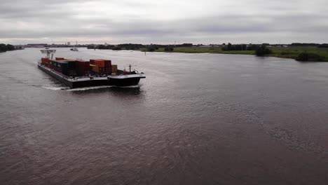 Aerial-View-Of-Pair-Of-Cargo-Container-Ship-And-Barge-Travelling-Along-River-Oude-Maas
