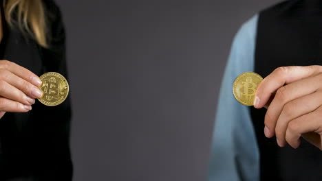 Detail-Einer-Männlichen-Und-Weiblichen-Hand,-Die-Zwei-Goldene-Bitcoin-Münzen-Hält,-Nahaufnahme