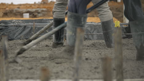 Rubber-Boots-In-Wet-Cement-At-Building-Site-As-Workers-Level-Concrete
