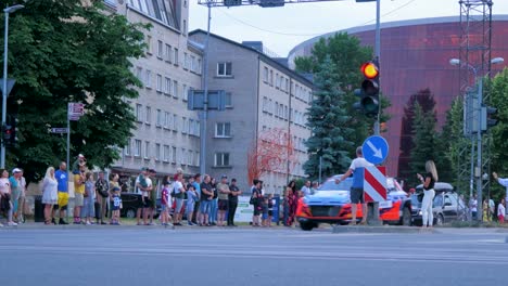 FIA-European-Rally-Trophy-2021-festive-start-and-cars-parade-at-streets-of-Liepaja-,-rally-cars-passing-spectators,-low-medium-angle-tracking-shot