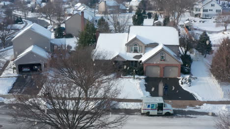 US-Mail-carrier-delivers-Christmas-package-gift-to-home-covered-in-winter-holiday-snow