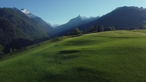 Green-alpine-meadow-in-Austria-with-snow-capped-mountain-peaks-in-the-background