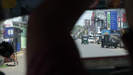 Looking-out-of-tuk-tuk-window-while-driving-through-busy-city-center-of-Negombo,-Sri-Lanka