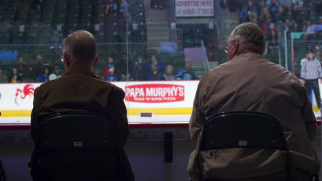 Two-elderly-fans-of-hockey-sitting-on-chairs-are-spectating-a-game-in-Town-Toyota-Center